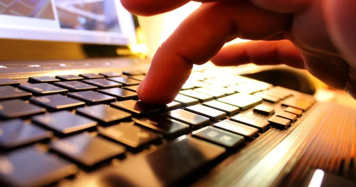 Close-up of a finger pressing a key on a laptop keyboard